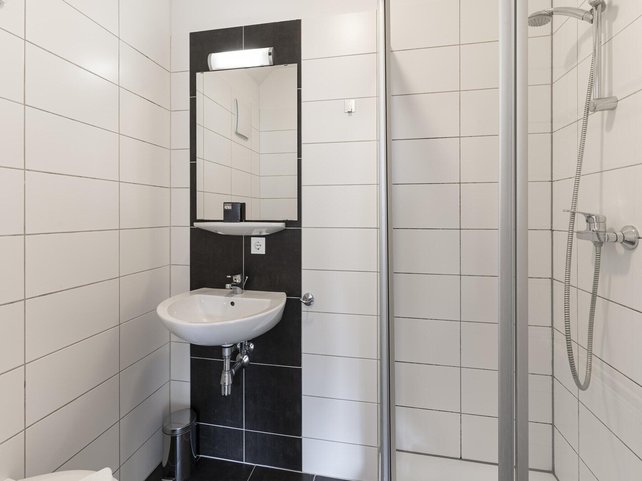 Ein Badezimmer mit einem weißen Waschbecken, einem Spiegel und einer Dusche.