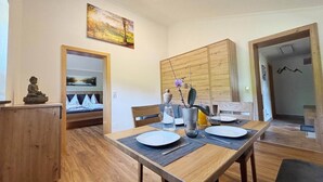 Un coin repas avec une table en bois dressée pour deux personnes, une statue de Bouddha et un tableau accroché au mur.
