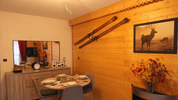 A cozy dining area with a wooden table set for four, a fireplace, and a framed wildlife painting.