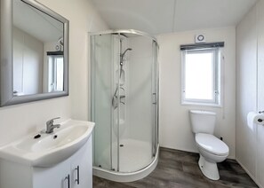 Un baño con ducha acristalada, un lavabo blanco y un inodoro.