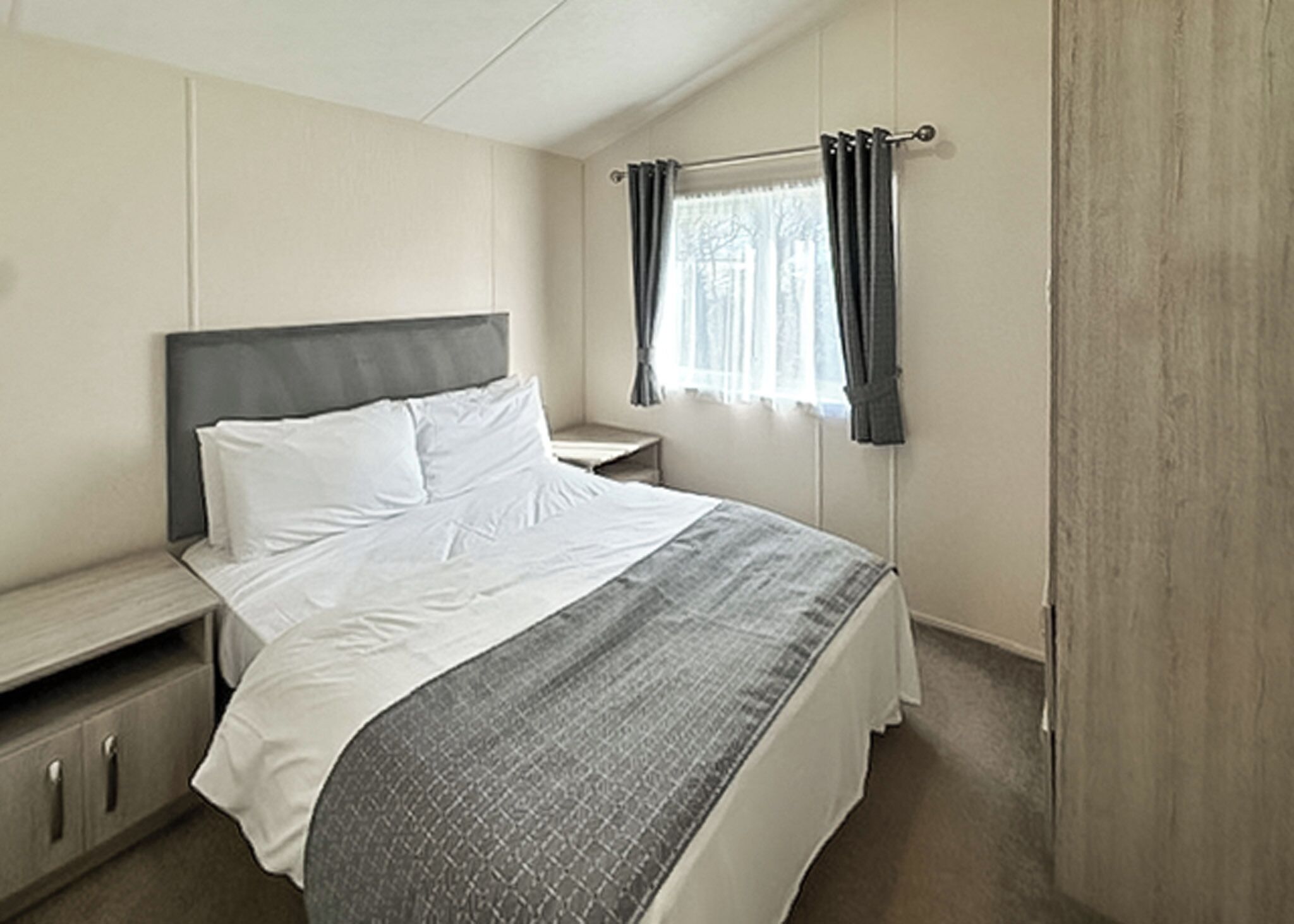 Une chambre à coucher avec un lit, une table de chevet et une fenêtre avec des rideaux.