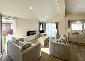 Una sala de estar con una televisión de pantalla plana, dos sofás, una mesa de centro y un ventanal corredizo que da a un patio.