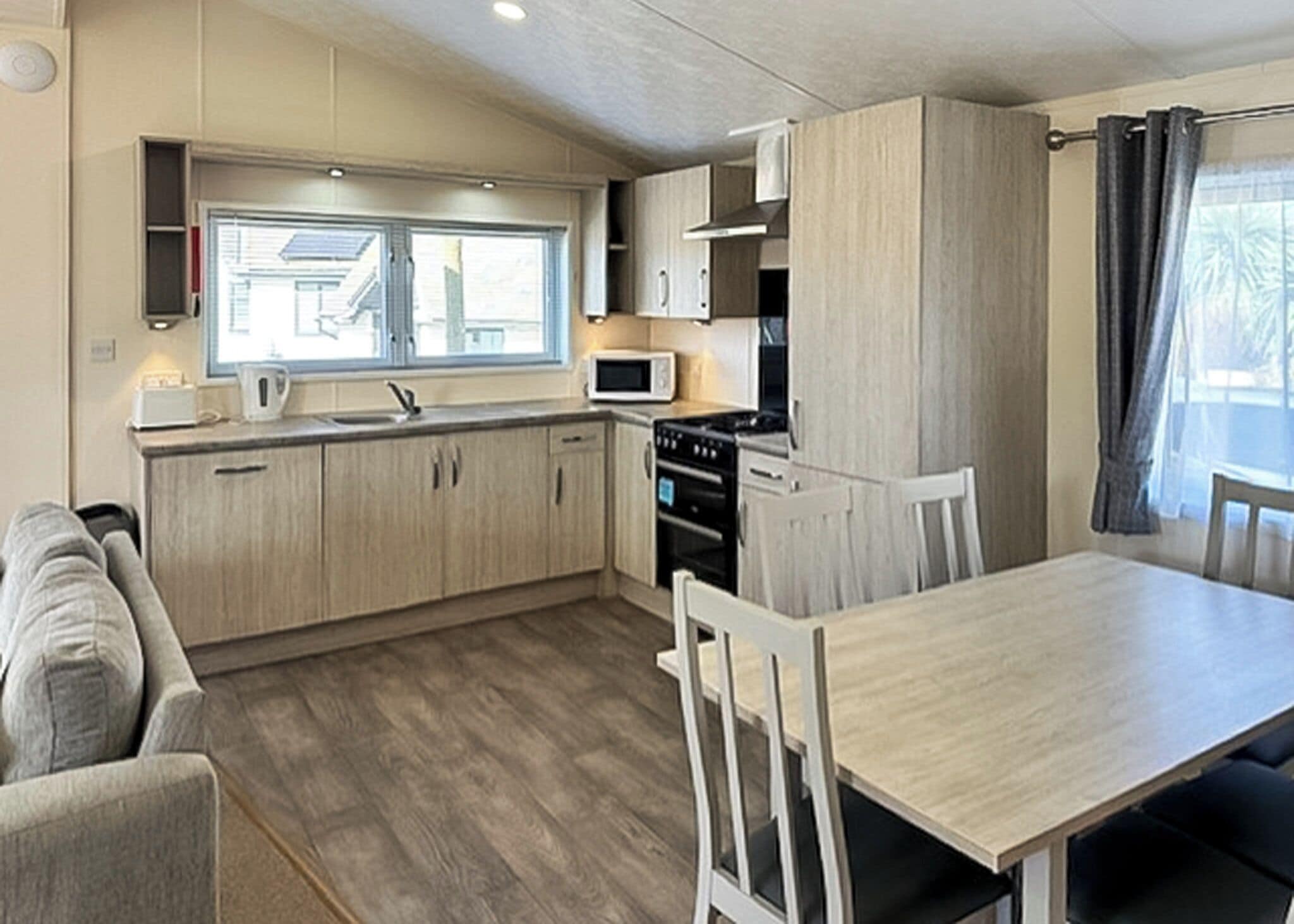 Een kleine keuken met een eettafel, stoelen, een magnetron en een fornuis.