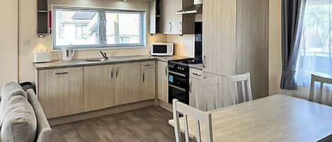 Een kleine keuken met een eettafel, stoelen, een magnetron en een fornuis.