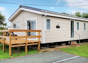 Una casa móvil con terraza de madera, puerta corrediza y un pequeño porche.