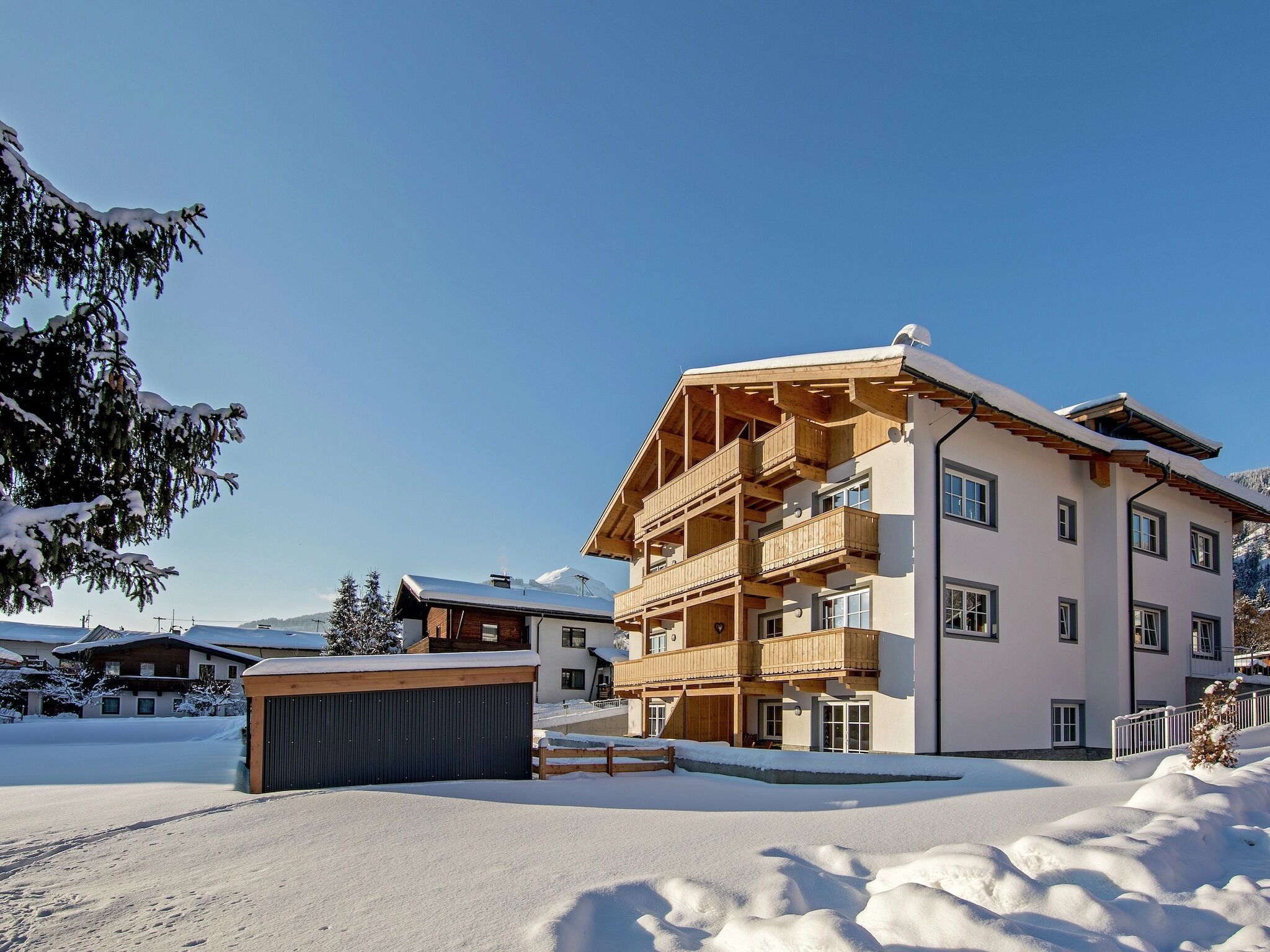 Un edificio de varios pisos con balcones, rodeado de nieve y árboles.