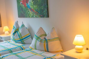 Habitación de hotel con cama, almohadas, mesita de noche, lámpara y un cuadro en la pared.