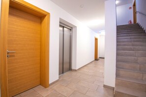 A hallway with a wooden door, a vertical elevator, and a staircase. - Modern Apartment in Brixen im Thale near Ski Area (Brixen im Thale)