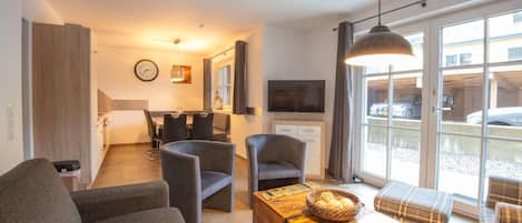 Una sala moderna con un sofá, sillones, una mesa de centro y un televisor.