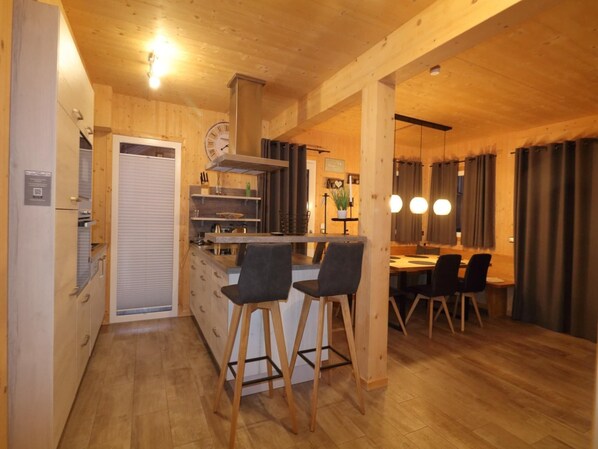 Un intérieur en bois comprenant une cuisine, un coin repas et des tabourets de bar.