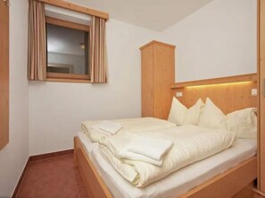 Una cama individual con cabecera de madera y una ventana con cortinas.