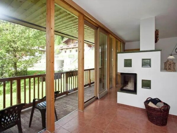 Un balcón con barandas de madera, una mesa, sillas y una chimenea.
