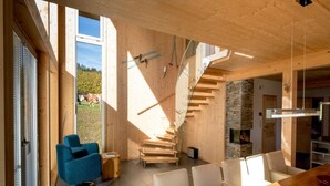A modern interior with a wooden staircase, a dining area, and a fireplace. - Chalet in Sankt Georgen on Ski Slopes (Kreischberg Murau)