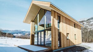 A modern wooden cabin with large glass windows, a sloped roof, and a wooden deck. - Chalet in Sankt Georgen on Ski Slopes (Kreischberg Murau)