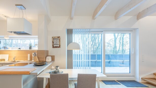 A modern kitchen with a large window, a dining area with two chairs, and a view of a snowy landscape.