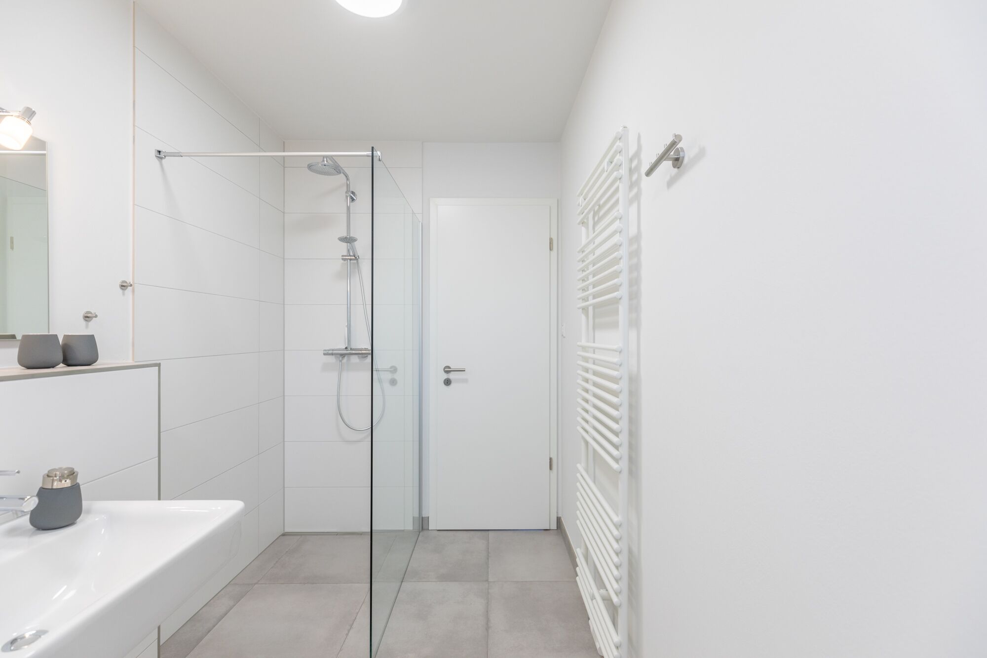 A modern bathroom with a glass-enclosed shower, a white bathtub, and a white toilet.