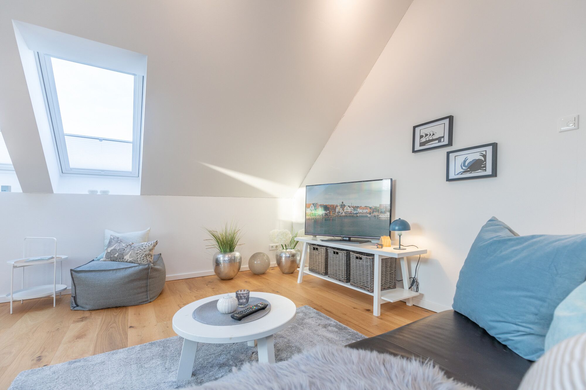 Ein modernes Loft-Wohnzimmer mit großem Fernseher, bequemen Sitzmöglichkeiten und einem Oberlicht.