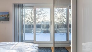 A bedroom with a large sliding glass door leading to a snowy outdoor area.