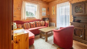 A cozy cabin interior with a wooden ceiling, a sofa with colorful cushions, a wooden table, and a red armchair. - Chalet in Turracher Höhe near Ski Slopes (Turracher Höhe)