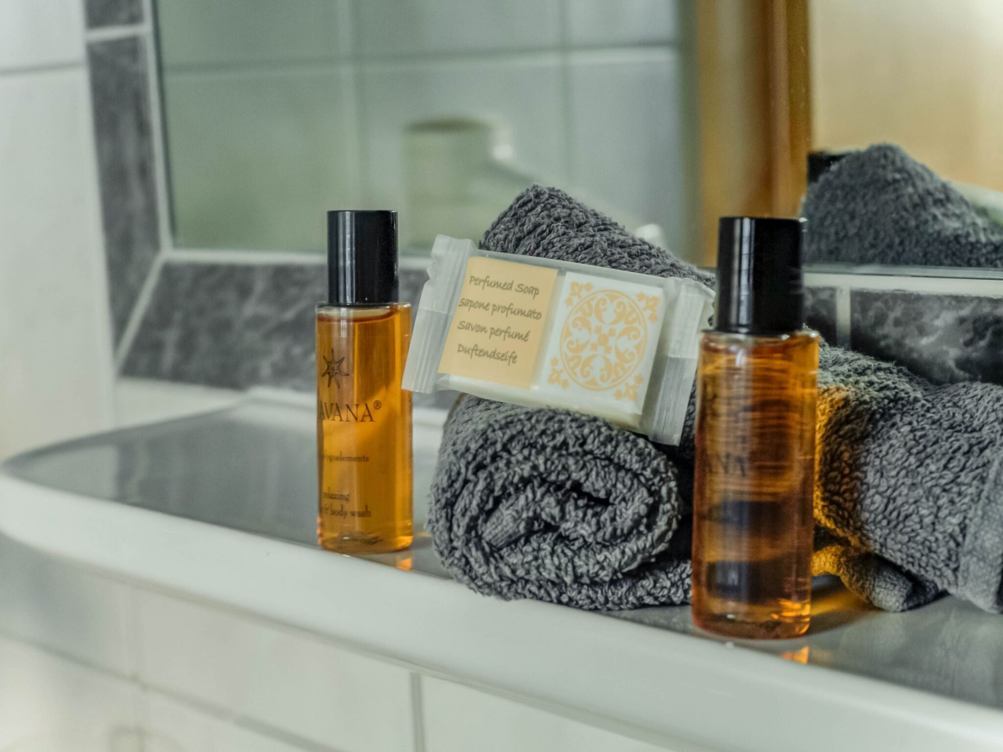 A bathroom with a white sink, two bottles of body wash, a bar of soap, and a towel.