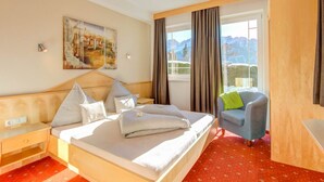 A hotel room with a bed, a chair, a desk, a painting, and a window with a mountain view. - Inviting Apartment in Fiss in the Mountains (Fiss)