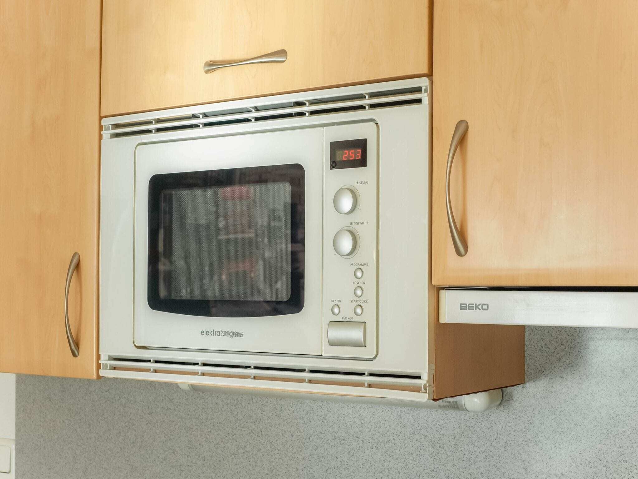 Een keuken met een inbouwmagnetron, een digitaal display en een bedieningspaneel met knoppen voor instellingen.