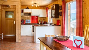 Un intérieur en bois comprenant une cuisine, un coin repas et une vue par une fenêtre.