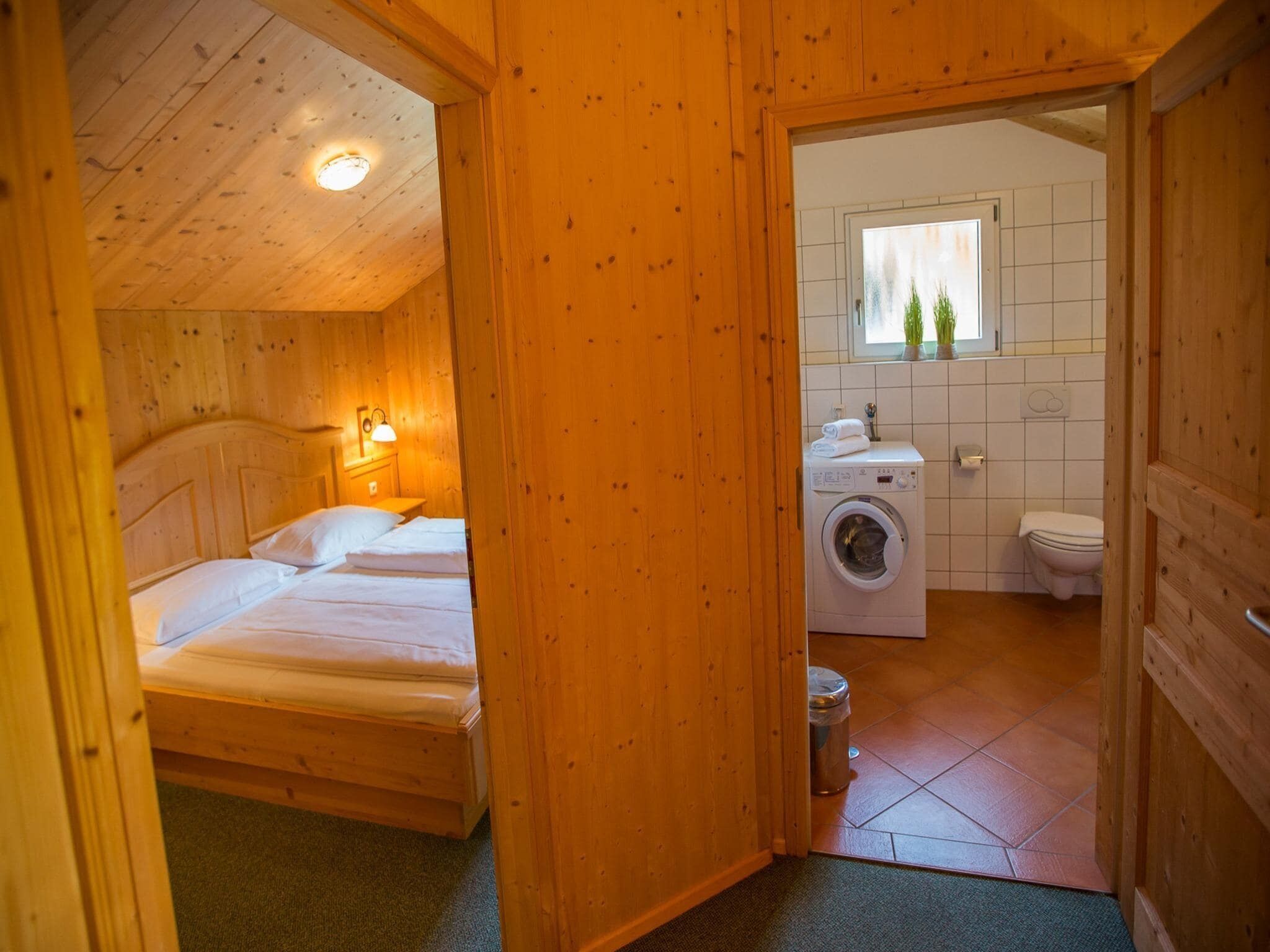 Une cabane en bois comprenant une chambre avec deux lits, un lave-linge et une salle de bain avec fenêtre.