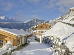 A wooden chalet with a balcony, surrounded by snow-covered mountains.