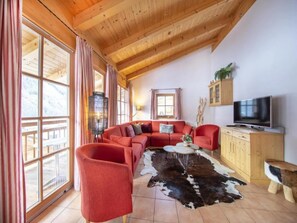 Una sala de estar acogedora con un sofá modular, una mesa de centro y un televisor.