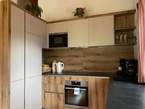Una cocina moderna con armarios de madera, microondas, cafetera y lavavajillas.