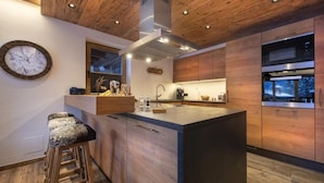 A modern kitchen with wooden cabinetry, a central island, and a clock on the wall.