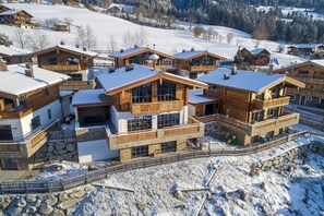 Un ensemble de chalets en bois dotés de balcons, situés sur une colline enneigée.