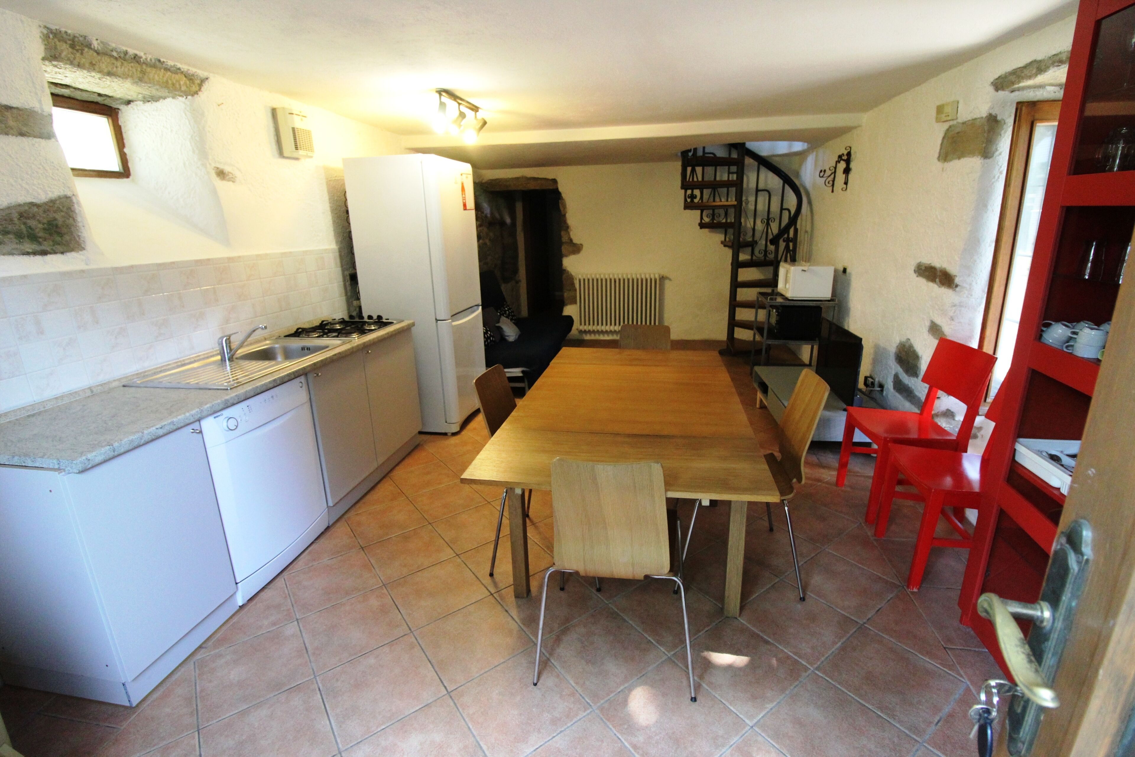 A compact kitchen with a dining table, chairs, and basic appliances.