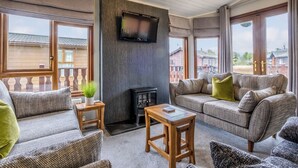 A cozy living room with a fireplace, comfortable seating, and large windows.