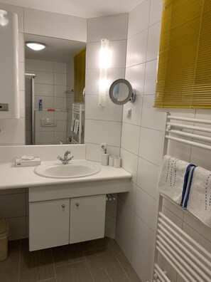 A modern bathroom with a white sink, mirror, and towel rack. - Cozy apartment overlooking a garden in a magnificent panoramic location (Landeck)