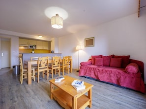 A compact living space with a dining area, a red sofa, and a wooden table.