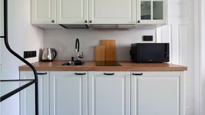 A kitchen with white cabinets, a wooden countertop, a kettle, a toaster, and a microwave.