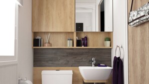 Een moderne badkamer met een wit wastafel, toilet en spiegel. Er zijn planken met toiletartikelen en een kleine plant.