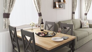 Een eethoek met een houten tafel, stoelen, een fles wijn, glazen en een bord eten.