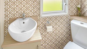 Un baño con lavamanos blanco, inodoro y papel tapiz estampado.