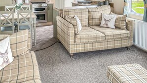 Una sala acogedora con sofá, una mesa de comedor con sillas, una cocina equipada y un ventanal con cortinas.