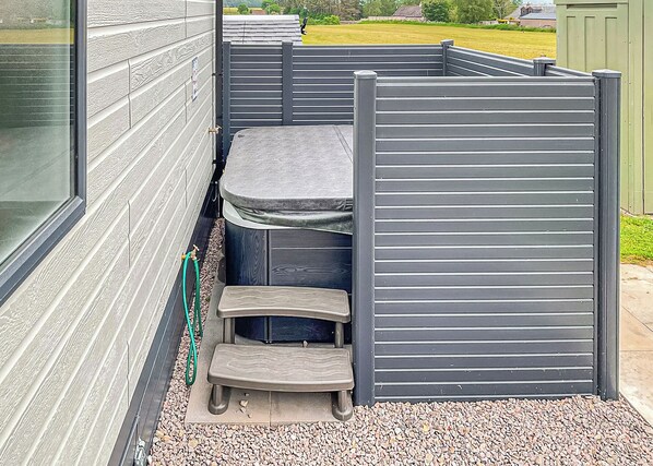 A small outdoor seating area with a table and steps, enclosed by a grey partition.