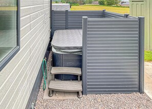 Un pequeño espacio al aire libre con una mesa y escalones, delimitado por una partición gris.