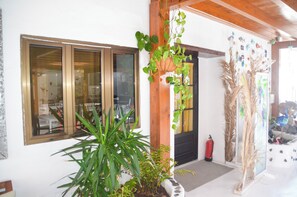 A building with large windows, a door, and a fire extinguisher near the entrance. - GA7COLORES (San Bartolome)