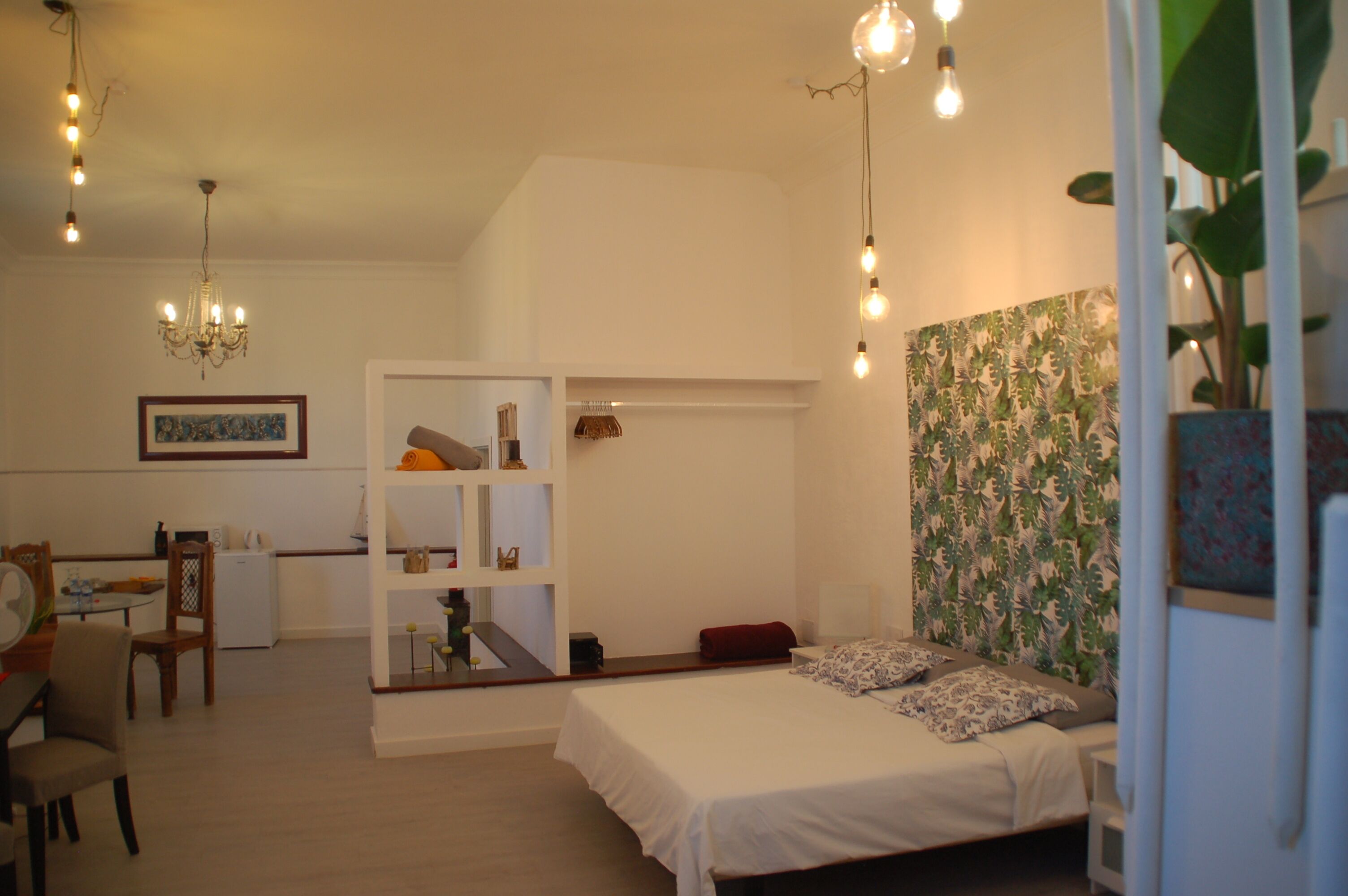 Un dormitorio con cama, mesita de noche, cómoda y silla. Se ve una ventana con vista al exterior.