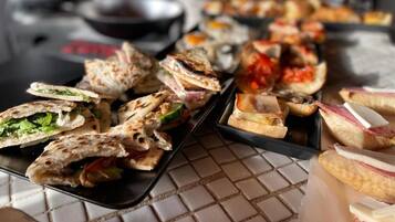 A variety of food items, including sandwiches and pastries, arranged on trays.