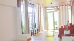 A hotel room with a large bed, a red armchair, a television, and a view of the outdoors. - GA7COLORES (San Bartolome)