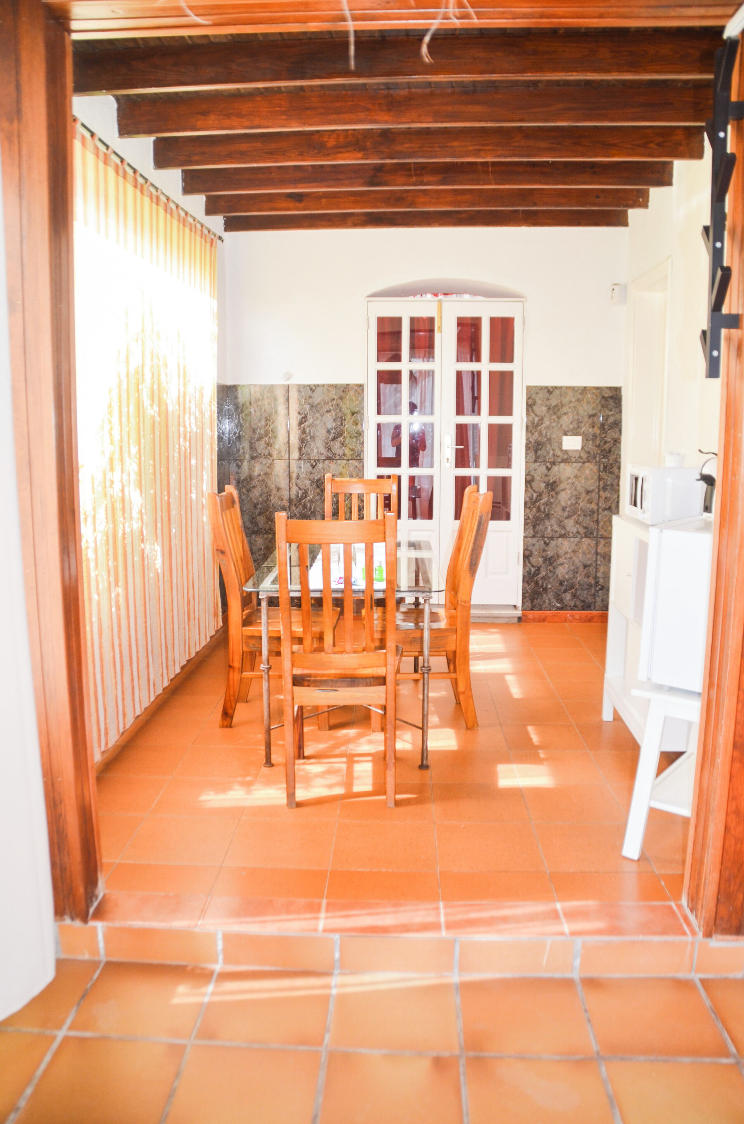 A dining area with a wooden table and chairs, a tiled floor, and a white cabinet.
