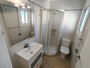 Une salle de bain avec une douche à parois de verre, un lavabo blanc et des toilettes.
